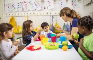 Children eating at a table with a nursery worker